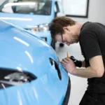 Professional automotive detailing products from premium brands displayed in a modern detailing studio with polishing machines, ceramic coatings, and microfiber towels.