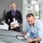 Professional detailing business owner managing a luxury vehicle detailing studio with trained technicians and modern equipment