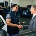 Professional detailer explaining a vehicle detailing process to a customer inside a modern automotive detailing studio