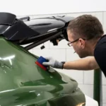 Professional detailer comparing paint protection film and ceramic coating on a premium vehicle inside a modern detailing studio